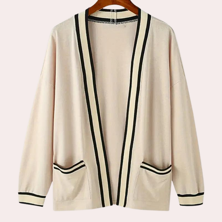 Beige cardigan met zwarte strepen, open voorkant en zakken, op houten hanger. Stijlvolle dameskleding, perfect voor casual en formele gelegenheden.