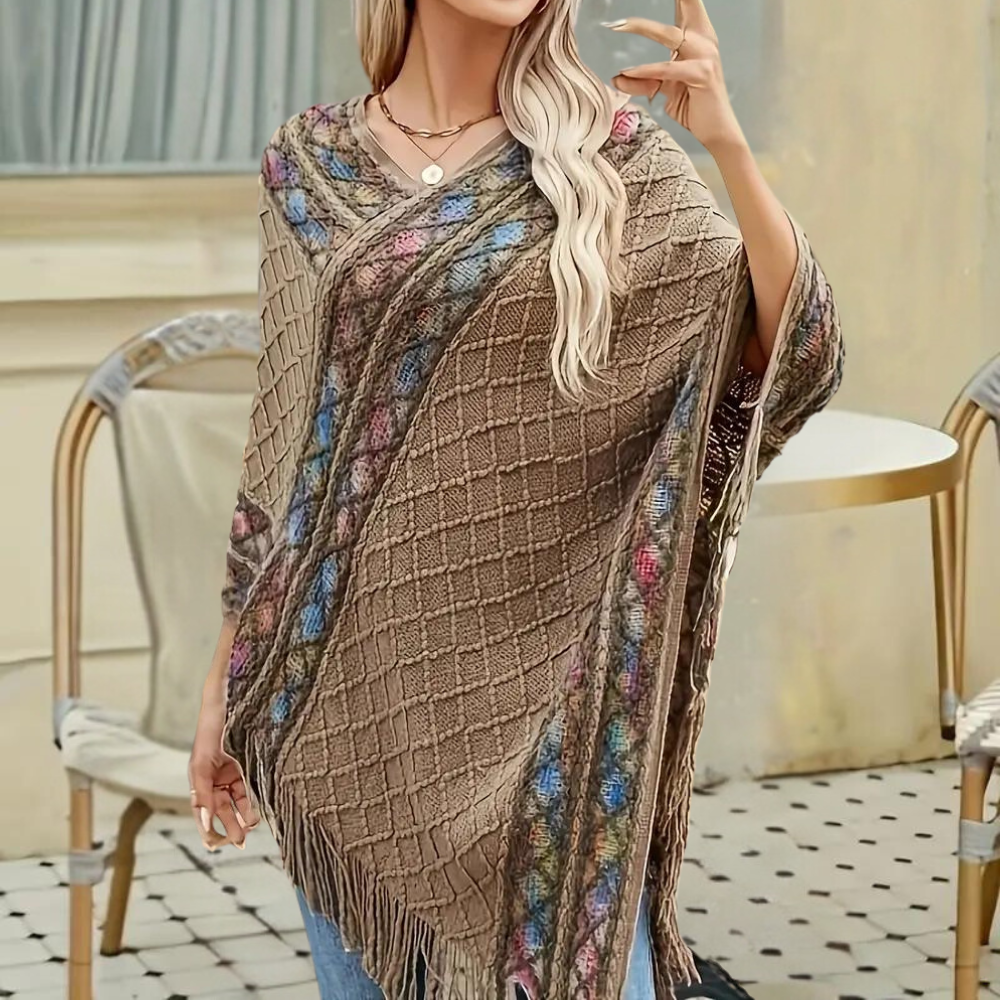 Vrouw draagt stijlvolle khaki poncho met kleurrijk patroon en franjes, perfect voor herfstmode. Ideaal voor casual en chique outfits.