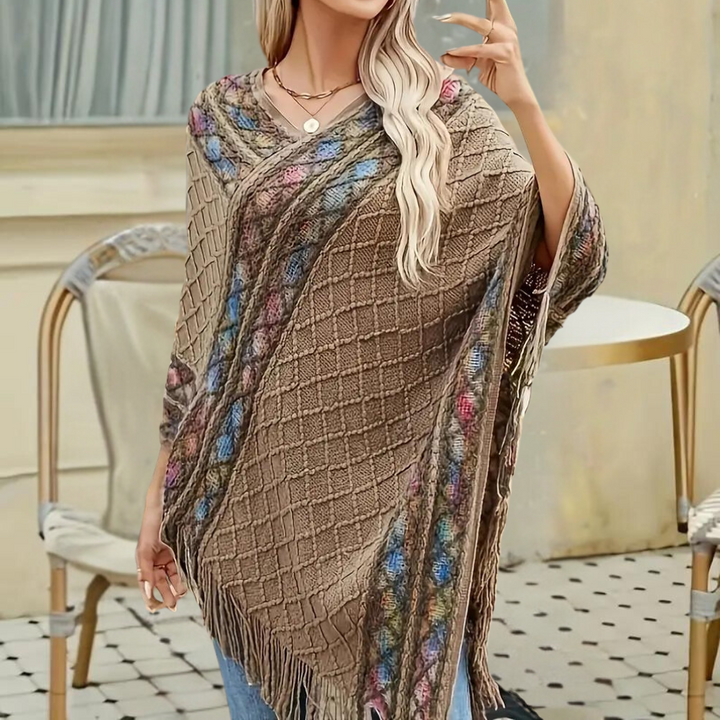 Vrouw draagt stijlvolle khaki poncho met kleurrijk patroon en franjes, perfect voor herfstmode. Ideaal voor casual en chique outfits.