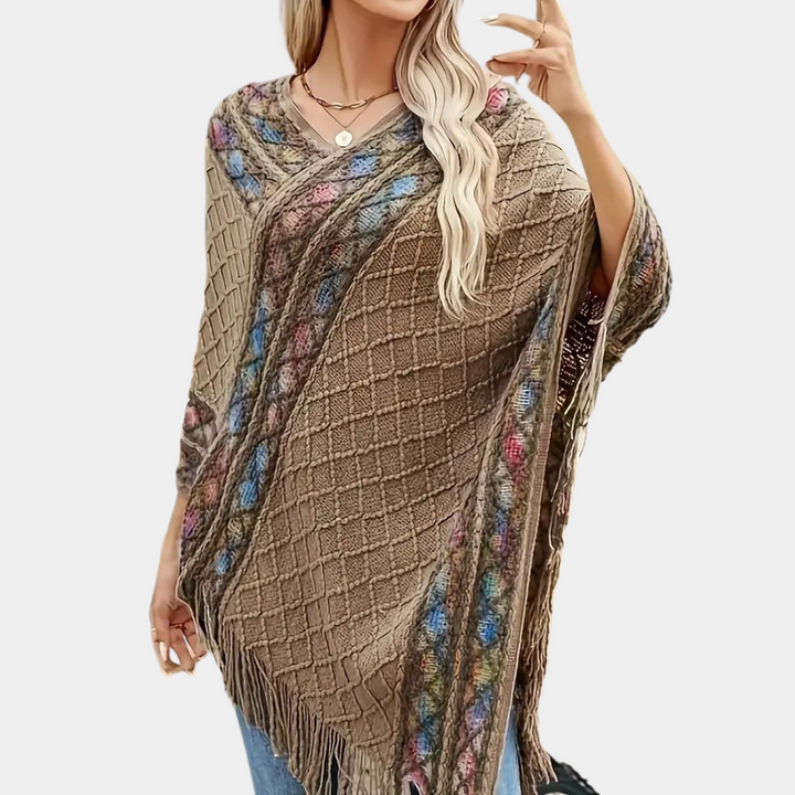 Vrouw draagt khaki poncho met kleurrijk patroon en franjes, perfect voor herfstmode. Stijlvolle dameskleding, casual en elegant design.