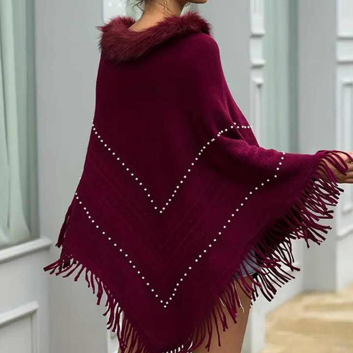 Bordeauxrode poncho met franjes en nepbontkraag, versierd met witte stippen. Stijlvolle damesmode, herfstkleding, warme poncho.