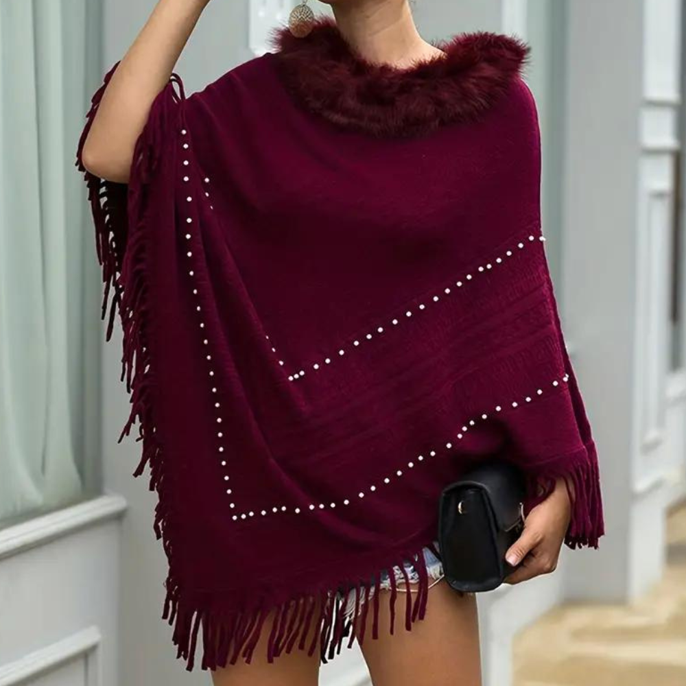 Vrouw draagt bordeauxrode poncho met parels en franjes, bontkraag, stijlvolle herfstmode, elegante dameskleding, trendy accessoire, straatstijl.
