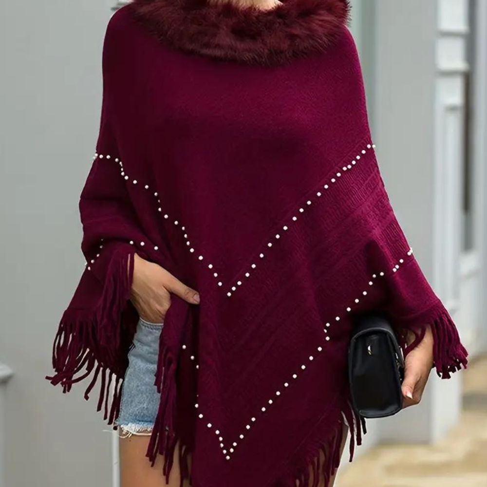 Rode poncho met bontkraag en pareldetails, gedragen door model. Stijlvolle damesmode, herfstkleding, warme poncho met franjes.