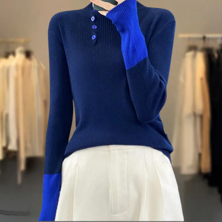 Donkerblauwe trui met kraag en knopen, lange mouwen, contrasterende blauwe manchetten, gedragen door model in kledingwinkel. Elegante damesmode.