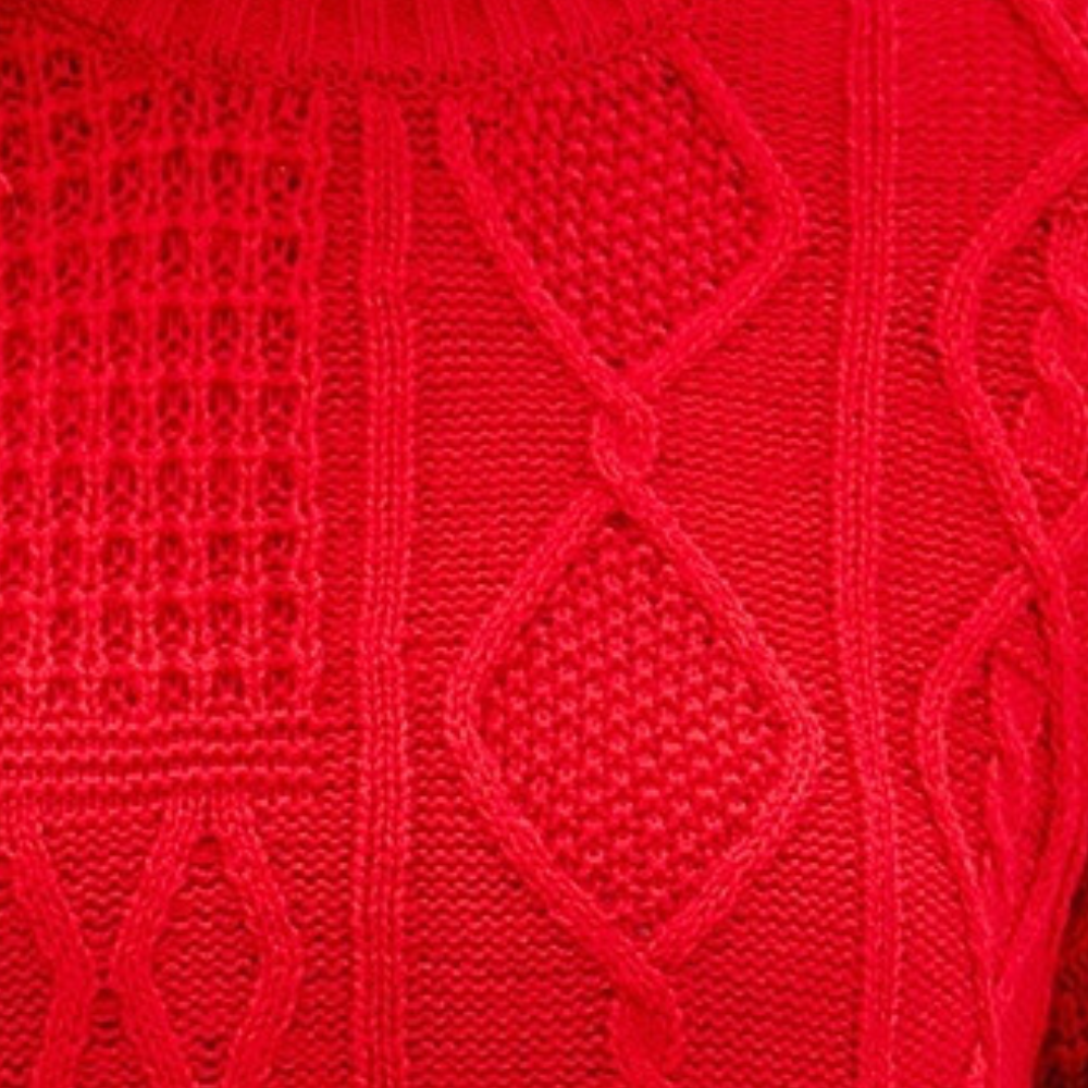 Rode gebreide trui met kabelpatroon, close-up textuur. Warme wintermode, stijlvolle dameskleding, trendy gebreide stof.