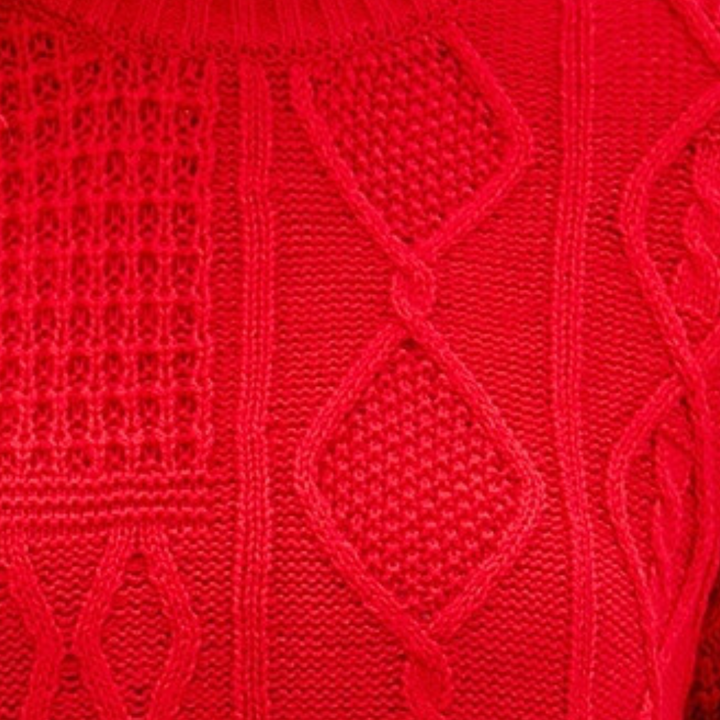Rode gebreide trui met kabelpatroon, close-up textuur. Warme wintermode, stijlvolle dameskleding, trendy gebreide stof.