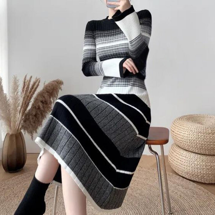 Gestreepte zwart-wit-grijze trui jurk, lange mouwen, zittend model, moderne minimalistische interieurstijl, trendy damesmode, herfst-winter outfit.