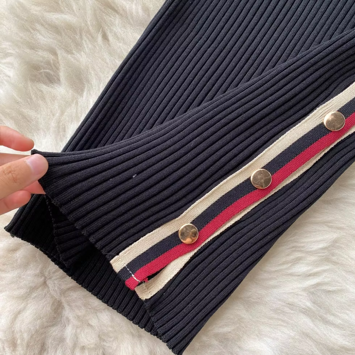 Zwarte geribbelde broek met gouden knopen en rood-witte streep op een witte pluchen achtergrond. Modieuze dameskleding, trendy design.