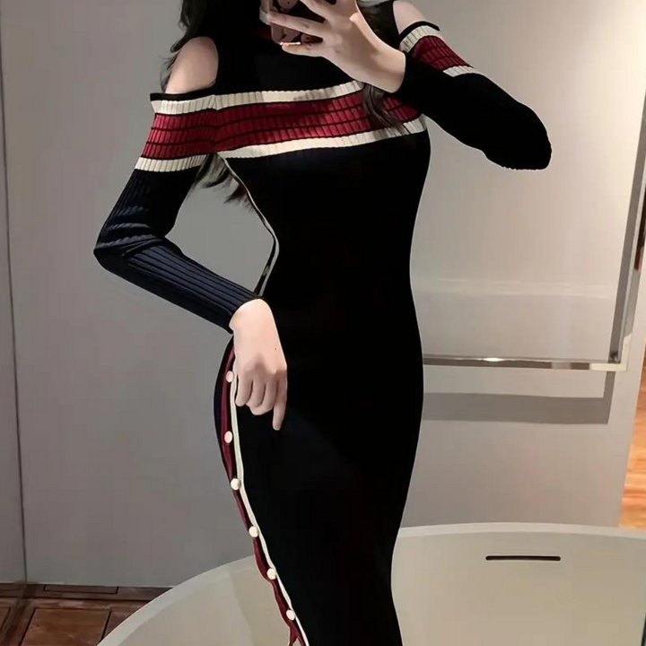 Elegante zwarte jurk met schouderuitsnijdingen, rode en witte strepen, en knoopdetails aan de zijkant. Perfect voor modieuze dameskleding.