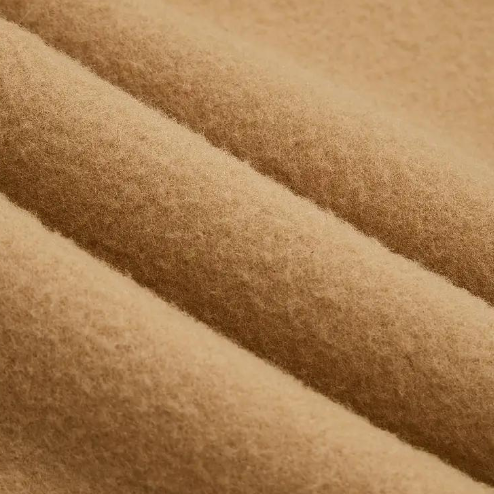 Close-up van beige wollen stof, zachte textuur, geschikt voor winterkleding en interieurdecoratie. Hoogwaardige wol, duurzaam en warm.