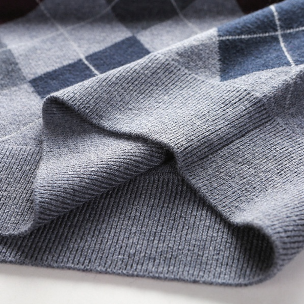 Grijze geruite wollen trui met argyle patroon, close-up van zachte stoftextuur. Perfect voor wintermode en stijlvolle herenkleding.