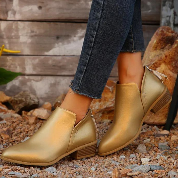Gouden enkellaarsjes met blokhak, gedragen op grindpad. Stijlvolle damesmode, perfect voor casual en chique outfits. Trendy schoenen 2023.