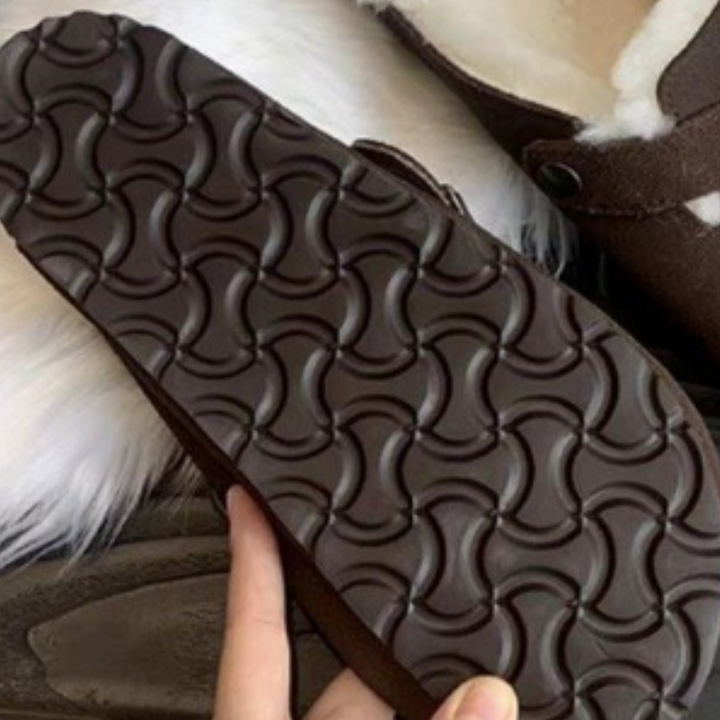 Bruine rubberen zool van een pantoffel met antislip patroon, ideaal voor binnengebruik. Comfortabele en warme pantoffels met schapenvacht voering.