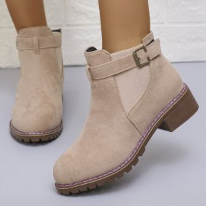 Beige suède enkellaarsjes met gesp, stevige zool en paarse stiksels. Modieuze dameslaarzen voor herfst en winter. Comfortabel en stijlvol.