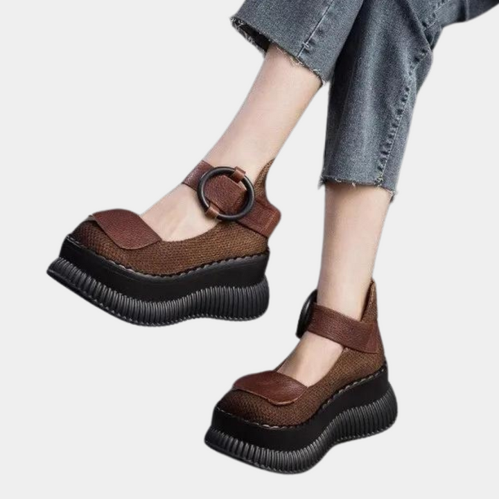 Donkerbruine damesplatformschoenen met dikke zwarte zool en verstelbare band, gedragen met opgerolde jeans. Trendy en comfortabel schoeisel.