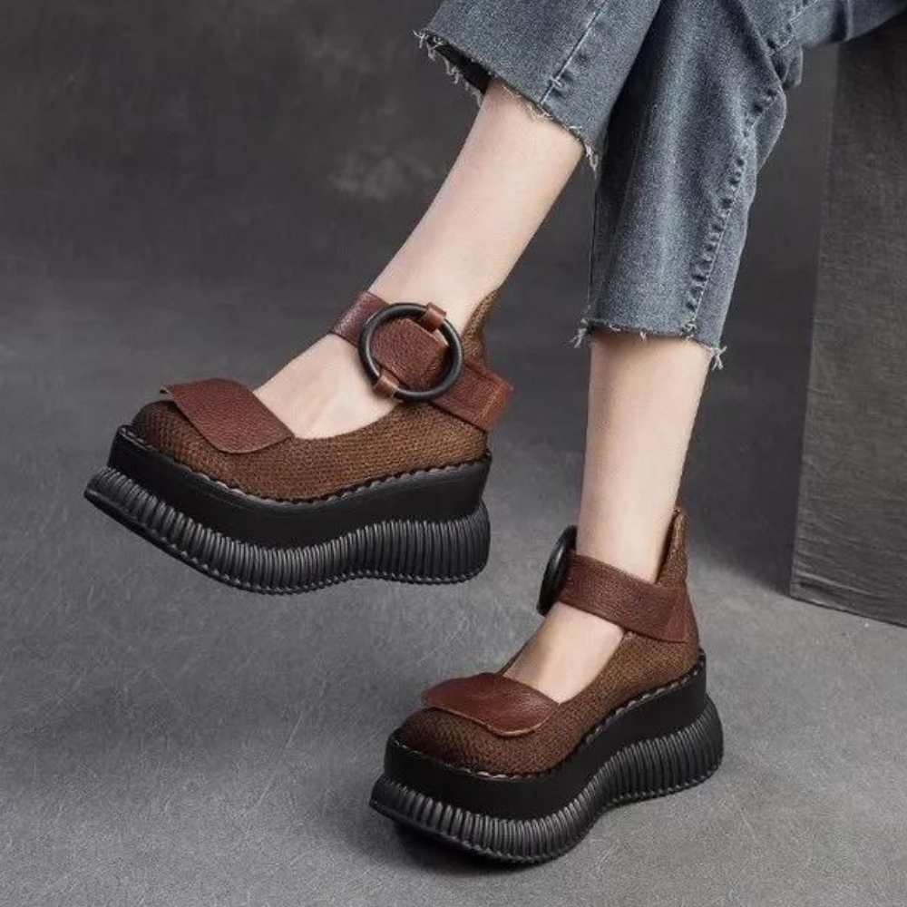 Bruine damesplatformschoenen met dikke zwarte zolen en verstelbare riem, gedragen met opgerolde spijkerbroek. Modieuze en comfortabele damesschoenen.