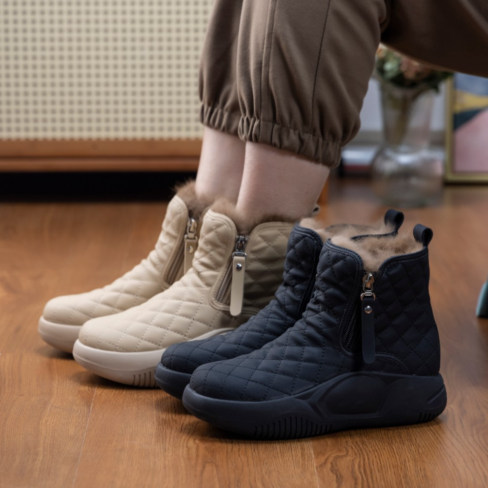 Twee paar gewatteerde winterlaarzen met ritssluiting en bontvoering, in beige en zwart, op houten vloer. Comfortabele dameslaarzen voor koude dagen.