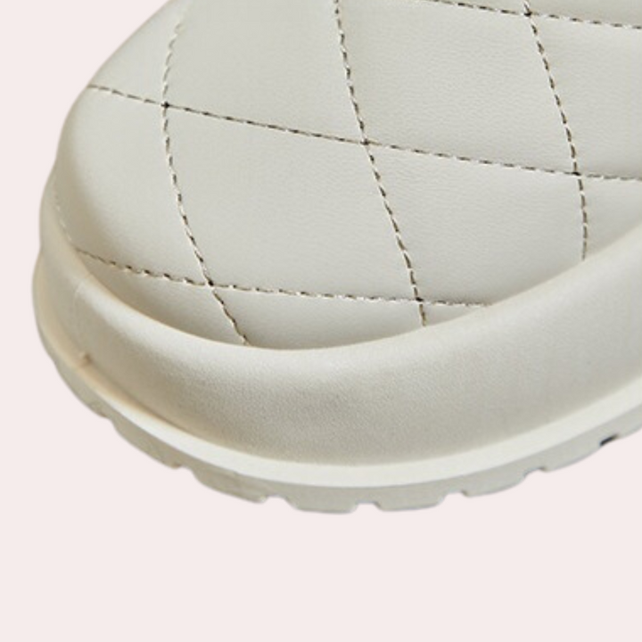 Witte gewatteerde leren slipper met stiksels, close-up. Comfortabele damesmode, trendy zomerschoen, luxe design, casual stijl.