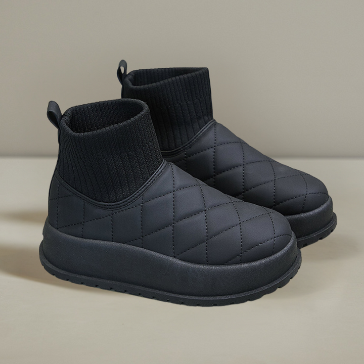 Zwarte gewatteerde enkellaarsjes met elastische sokboord, comfortabele zool en minimalistisch design. Perfect voor casual en winterse outfits.