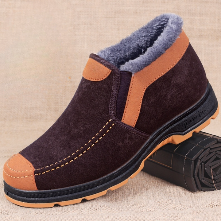 Bruine suède winterlaars met warme voering, antislipzool en oranje accenten. Perfect voor herenmode en winterse outdooractiviteiten.
