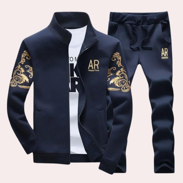 Donkerblauw trainingspak voor heren met gouden opdruk, bestaande uit een jas en broek. Ideaal voor sport en casual mode. Comfortabel en stijlvol.