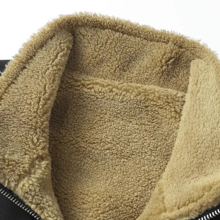 Zwarte jas met beige sherpa voering, ritsdetail zichtbaar. Warme winterjas, modieus en comfortabel. Perfect voor koude weersomstandigheden.