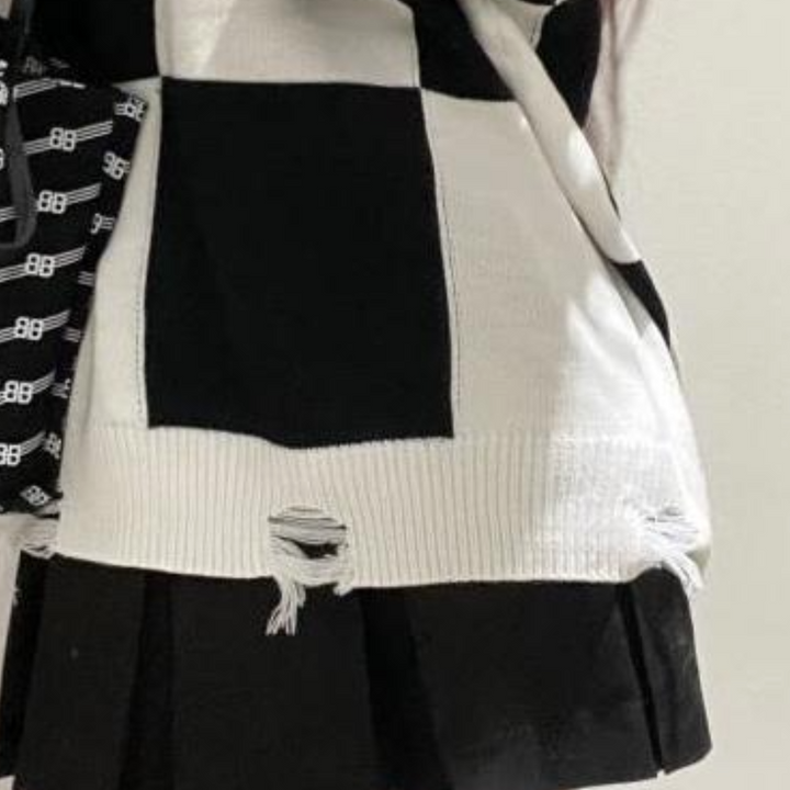 Zwart-witte geruite trui met rafels en beschadigde details, modieuze streetwear, trendy kleding, close-up textuur en ontwerp.