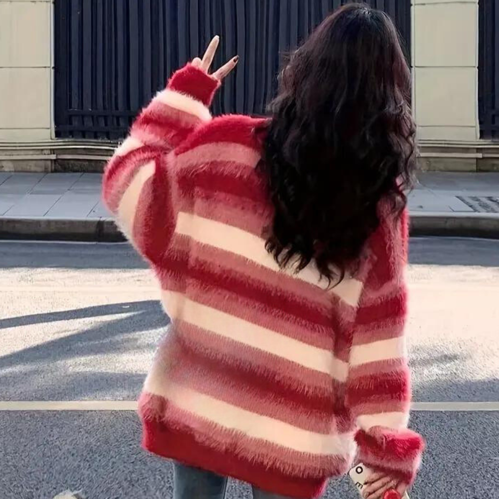 Vrouw in rood-wit gestreepte trui, rugaanzicht, maakt vredesteken. Modieuze winterkleding, casual straatstijl, trendy damesmode.
