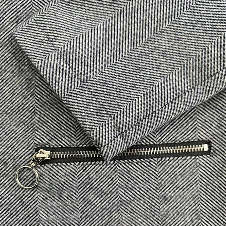 Grijze visgraatstof met metalen ritssluiting en ringtrekker, detailopname. Perfect voor modeontwerp, textiel en kledingproductie.