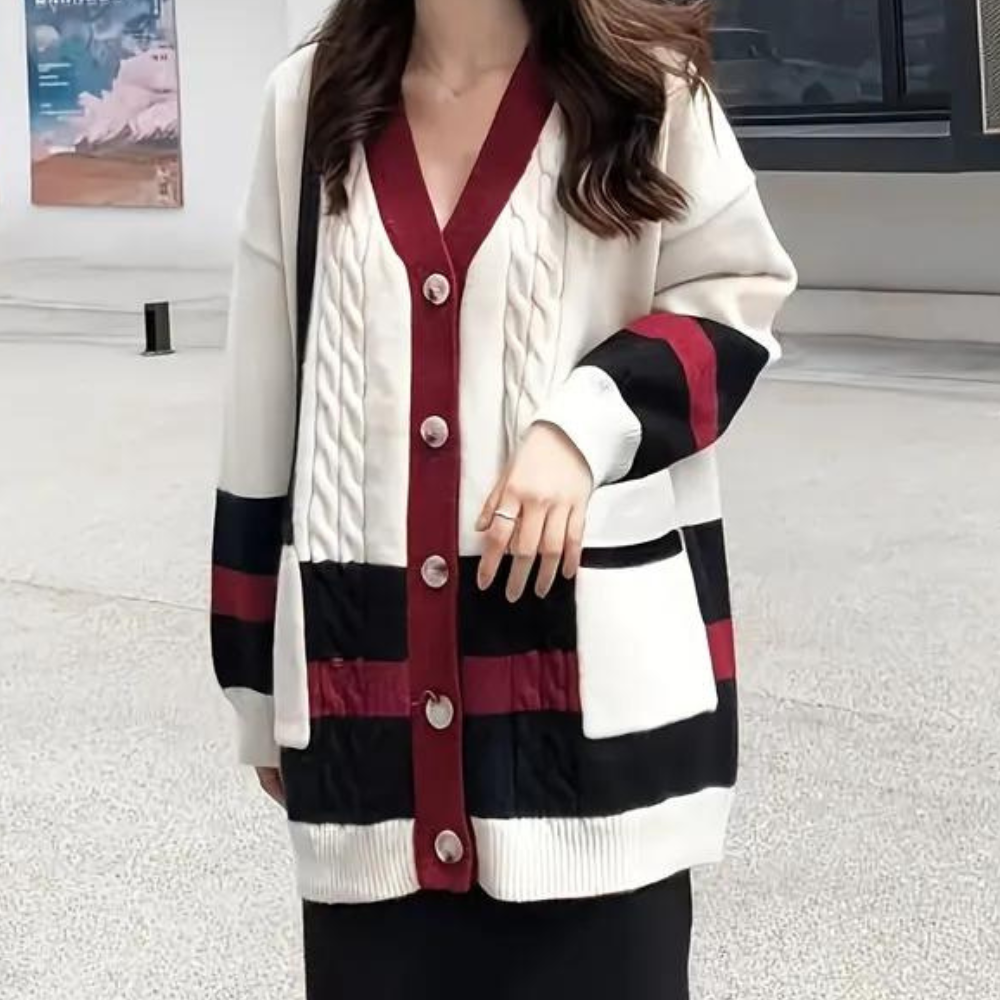 Vrouw draagt stijlvolle, oversized gebreide cardigan met knopen, rood-wit-zwart patroon. Perfect voor herfstmode en casual outfits.