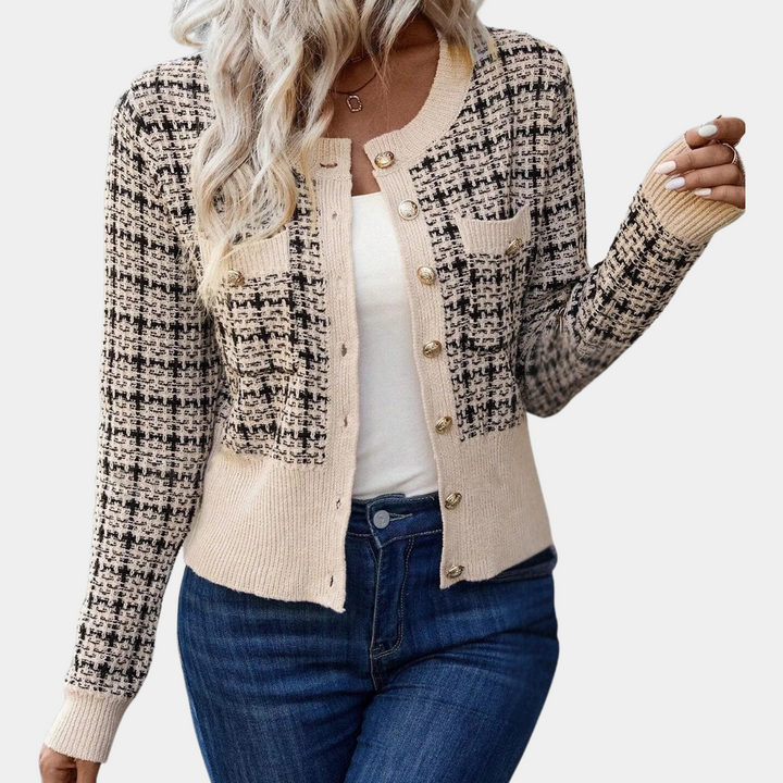 Vrouw draagt stijlvolle geruite cardigan met knopen, beige en zwart patroon, gecombineerd met witte top en blauwe jeans. Modieuze dameskleding.