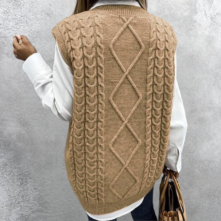 Dames gebreide kabeltrui in beige, gedragen over een witte blouse. Modieuze herfstkleding, perfect voor casual en stijlvolle outfits.