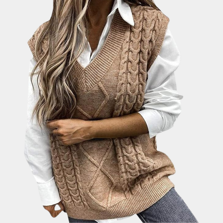 Vrouw draagt beige kabelgebreide spencer over witte blouse, modieuze herfstkleding, casual stijl, trendy damesmode, comfortabele outfit.