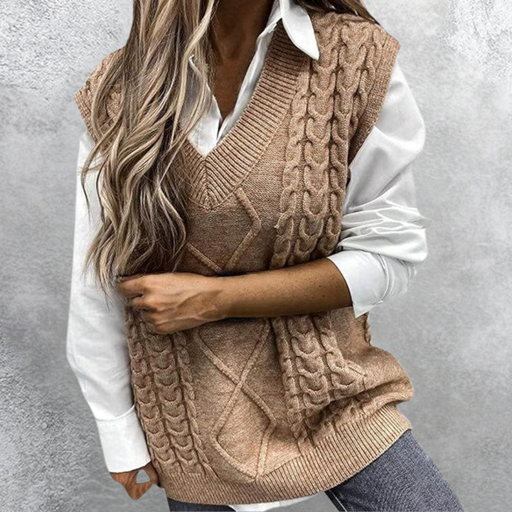 Vrouw draagt beige kabelgebreide spencer over witte blouse, modieuze herfstkleding, casual stijl, trendy damesmode, comfortabele outfit.