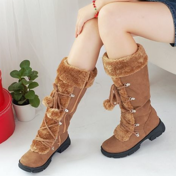 Bruine dameslaarzen met bontvoering en veters, comfortabele winterlaarzen, trendy en warm, perfect voor koude dagen, naast een groene plant.