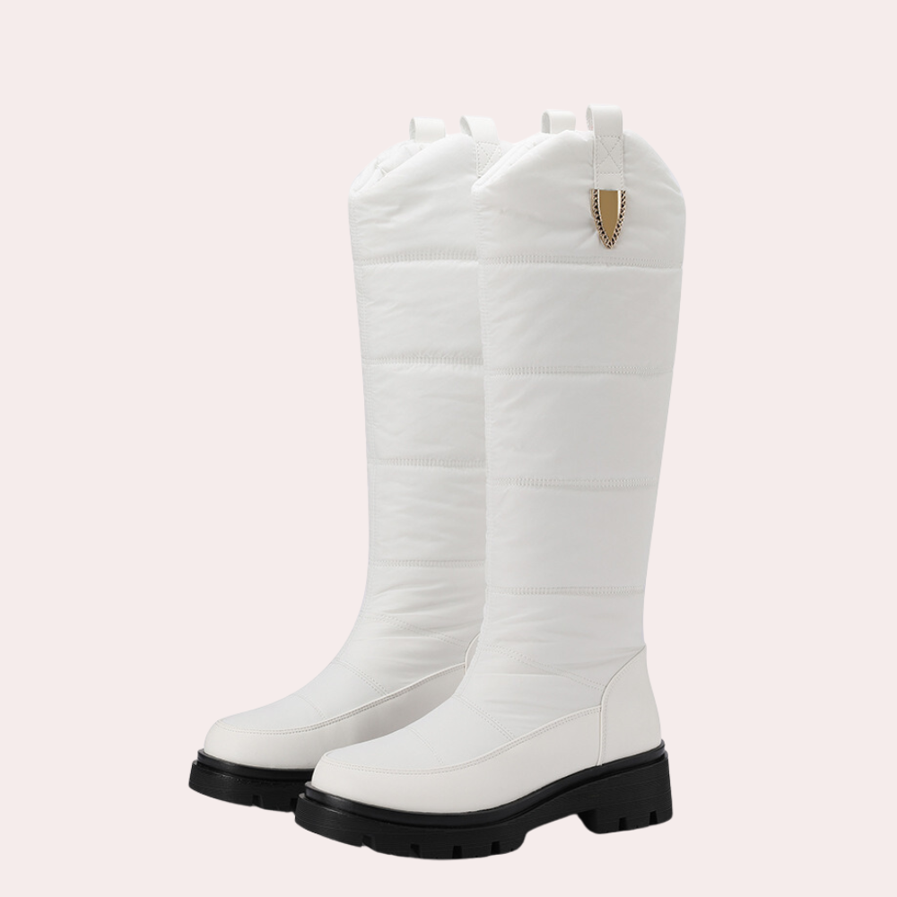 Witte kniehoge laarzen met dikke zwarte zool, gewatteerd ontwerp en gouden detail. Modieuze winterlaarzen voor dames, ideaal voor koude seizoenen.