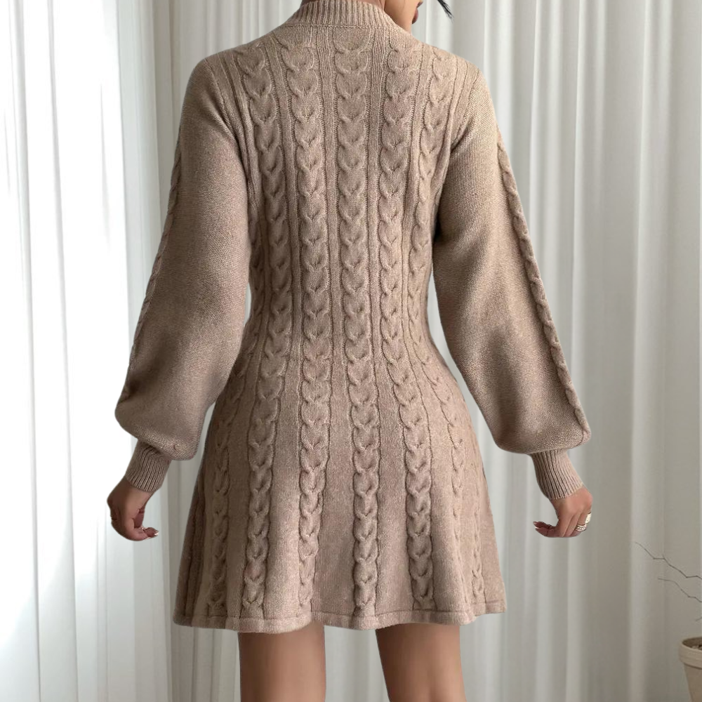 Beige gebreide jurk met kabelpatroon, lange mouwen en hoge hals. Perfect voor herfstmode, elegant en comfortabel. Ideaal voor casual en chique gelegenheden.