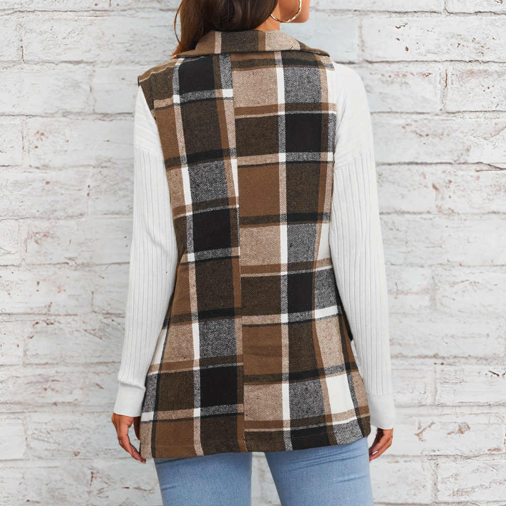 Vrouw draagt geruite bruine en zwarte vest met witte mouwen, tegen bakstenen muur. Modieuze dameskleding, herfststijl, casual outfit.