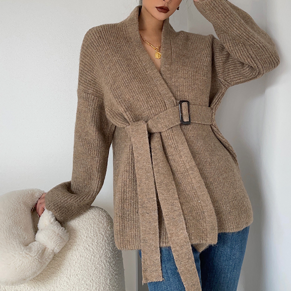 Vrouw draagt een bruine gebreide cardigan met ceintuur, gecombineerd met blauwe jeans. Stijlvolle herfstmode, comfortabele dameskleding.