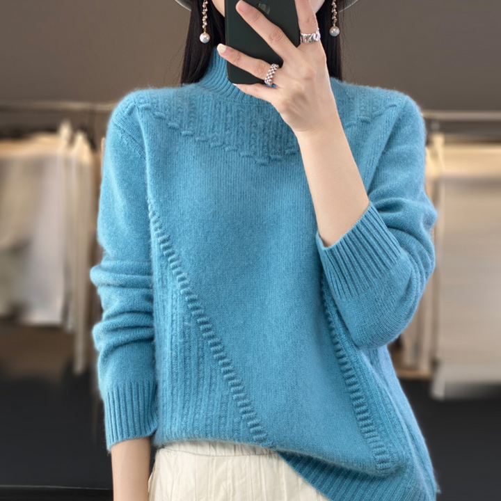 Vrouw in blauwe trui met geometrisch breipatroon, lange mouwen en hoge hals, poseert voor spiegel. Modieuze dameskleding, herfst/winter stijl.