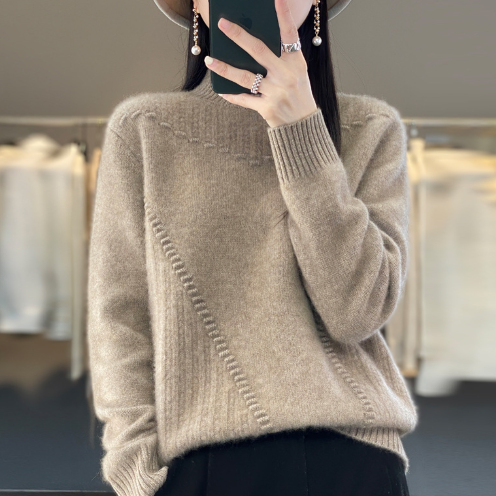 Vrouw in beige trui met gebreid patroon, draagt hoed en oorbellen, houdt smartphone vast. Modieuze herfstkleding, casual stijl.