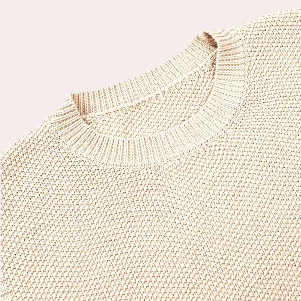 Beige gebreide trui met ronde hals, close-up detail. Modieuze dameskleding, comfortabele textuur, ideaal voor herfst- en winterseizoen.