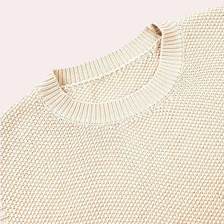 Beige gebreide trui met ronde hals, close-up detail. Modieuze dameskleding, comfortabele textuur, ideaal voor herfst- en winterseizoen.
