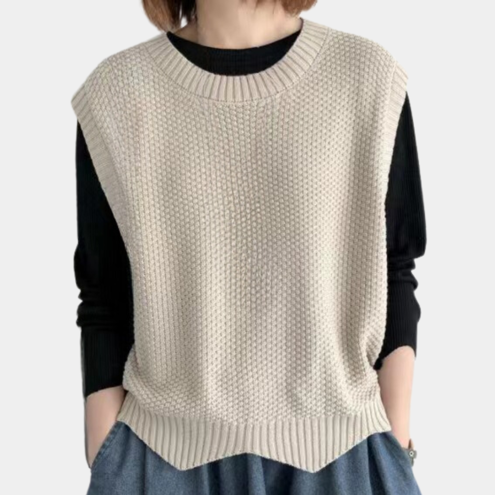 Beige gebreide dames spencer, mouwloos, over zwarte trui. Modieuze casual outfit, ideaal voor herfst- en winterlagen. Comfortabel en stijlvol.