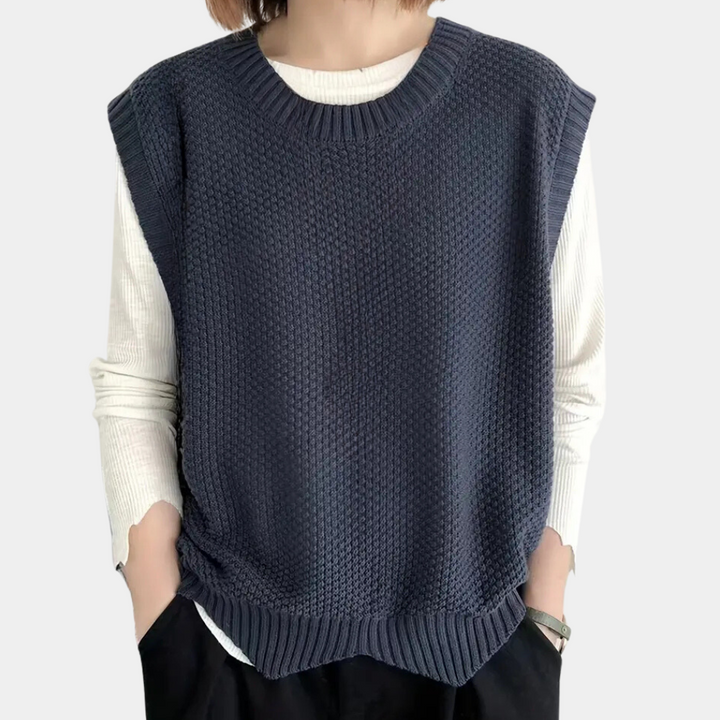 Donkerblauwe gebreide spencer voor dames, gedragen over een witte longsleeve. Modieuze, casual stijl, perfect voor herfst- en winterlagen.