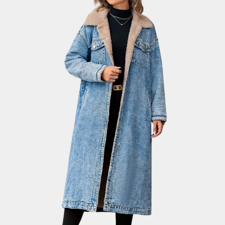 Vrouw in lange blauwe spijkerjas met schapenvachtkraag, zwarte coltrui en kettingen. Modieuze winteroutfit, trendy damesmode.