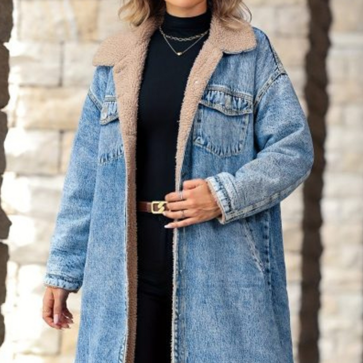 Vrouw in lange blauwe spijkerjas met bruine kraag, zwarte coltrui en riem. Modieuze winteroutfit, casual denim stijl.