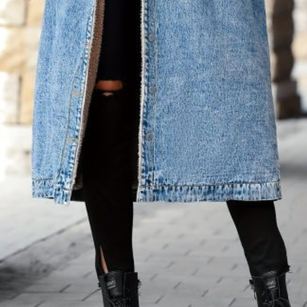 Dames lange blauwe spijkerjas, knoopsluiting, gedragen met zwarte broek en laarzen. Modieuze winterkleding, casual streetwear stijl.