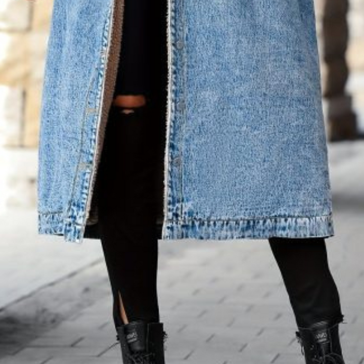 Dames lange blauwe spijkerjas, knoopsluiting, gedragen met zwarte broek en laarzen. Modieuze winterkleding, casual streetwear stijl.