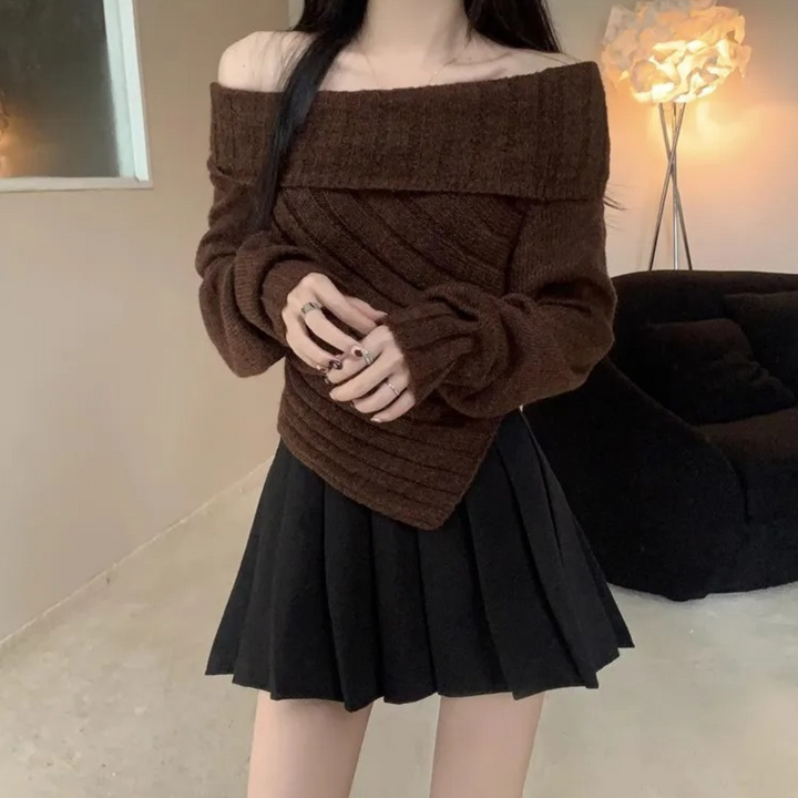 Vrouw in bruine off-shoulder trui en zwarte plooirok, moderne herfstmode, stijlvolle outfit, binnenhuis, trendy kledingstijl.